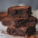 Brownie de chocolate recién horneado con helado y nueces, servido en un plato blanco.