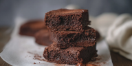 Brownie de chocolate recién horneado con helado y nueces, servido en un plato blanco.